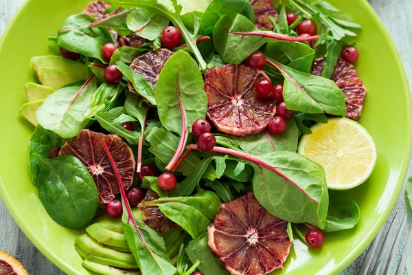 Fresh spring salad with arugula, beet leaves, avocado, red orange slices and cranberry — Stock Photo, Image
