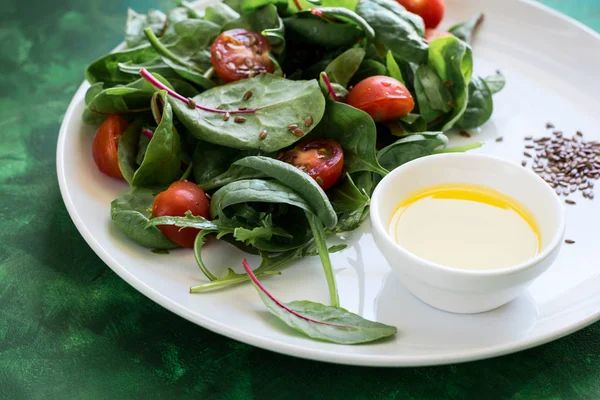 Свежий весенний вегетарианский салат с салатом, помидорами черри, оливковым маслом и семенами льна — стоковое фото