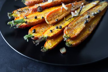 Kavrulmuş bahar havuç sarımsak, biber bezelye ve kişniş ile siyah plaka üzerinde