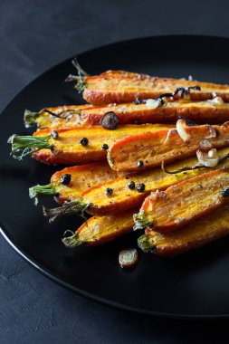 Kavrulmuş bahar havuç sarımsak, biber bezelye ve kişniş ile siyah plaka üzerinde