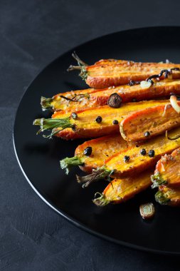 Kavrulmuş bahar havuç sarımsak, biber bezelye ve kişniş ile siyah plaka üzerinde