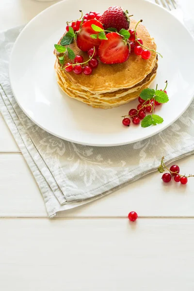 Завтрак: стопка блинов с ягодами, украшенная листьями мяты — стоковое фото