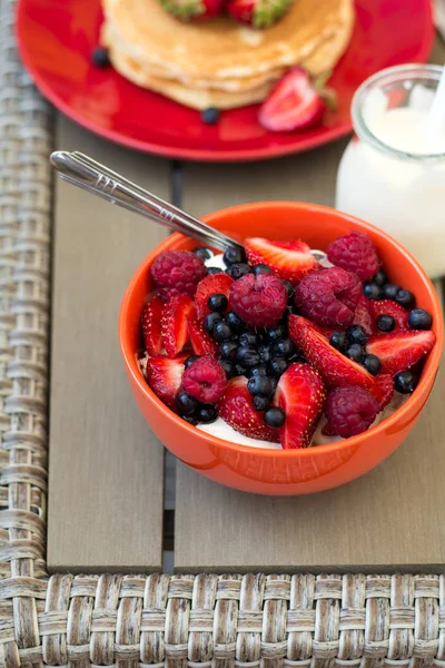 Colazione sana su mobili da giardino: ricotta con panna acida, fragola, lampone e mirtillo, frittelle, yogurt e succo di frutta — Foto Stock