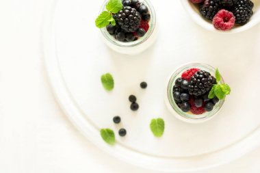 Sağlıklı Kahvaltı: yoğurt çilek, yaban mersini ve blackberry ile dekore edilmiş nane yaprakları Beyaz ahşap tablo