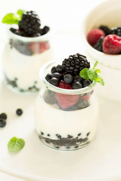 Gesundes Frühstück: Joghurt mit Erdbeeren, Blaubeeren und Brombeeren dekorierten Minzblättern auf weißem Holztisch — Stockfoto