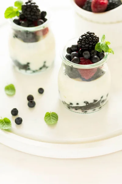 Gesundes Frühstück: Joghurt mit Erdbeeren, Blaubeeren und Brombeeren dekorierten Minzblättern auf weißem Holztisch — Stockfoto