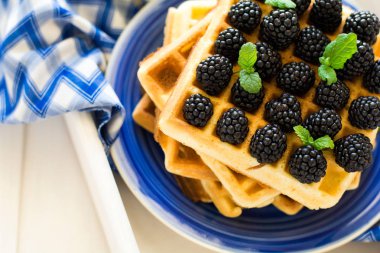 Sağlıklı Kahvaltı: böğürtlen ile Belçika waffle bal ve dekore edilmiş nane yaprakları ve mavi peçete süt 