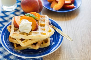 Sağlıklı Kahvaltı: Belçika waffle şeftali dilimleri ve krema ile dekore edilmiş olan nane yaprakları ve mavi peçete 