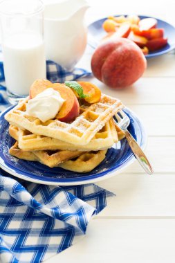 Sağlıklı Kahvaltı: Belçika waffle şeftali dilimleri ve krema ile dekore edilmiş olan nane yaprakları ve mavi peçete 