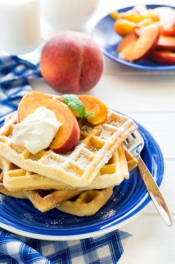 Sağlıklı Kahvaltı: Belçika waffle şeftali dilimleri ve krema ile dekore edilmiş olan nane yaprakları ve mavi peçete 