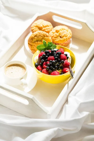 Träbricka med välsmakande frukost på sängen. Espresso, banana muffins, keso med blåbär och hallon — Stockfoto