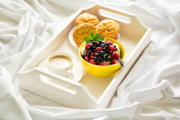 Träbricka med välsmakande frukost på sängen. Espresso, banana muffins, keso med blåbär och hallon — Stockfoto