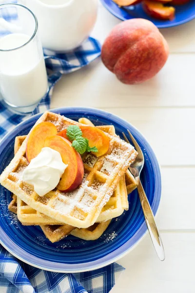 Sağlıklı Kahvaltı: Belçika waffle şeftali dilimleri ve krema ile dekore edilmiş olan nane yaprakları ve mavi peçete 