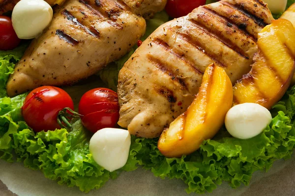 BBQ: peito de frango grelhado, tomates, fatias de pêssego e mini mussarela na mesa de madeira — Fotografia de Stock