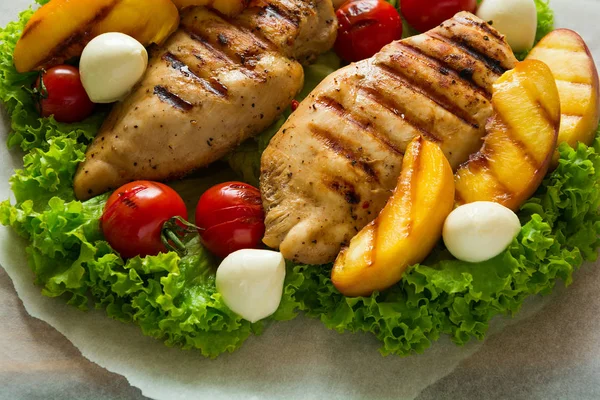 BBQ: peito de frango grelhado, tomates, fatias de pêssego e mini mussarela na mesa de madeira — Fotografia de Stock