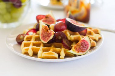 Sağlıklı Kahvaltı: incir, üzüm ve beyaz masa örtüsü karamel ile Belçika waffle. Seçici odak