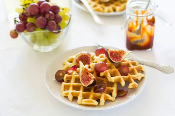 Gesundes Frühstück: belgische Waffeln mit Feigen, Trauben und Karamell auf weißer Tischdecke. Selektiver Fokus — Stockfoto
