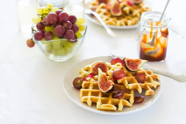 Gesundes Frühstück: belgische Waffeln mit Feigen, Trauben und Karamell auf weißer Tischdecke. Selektiver Fokus — Stockfoto