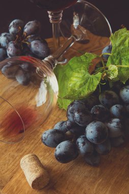 İki kadehlerin kırmızı şarap ve üzüm asma yaprağı koyu ahşap masa üzerine dekore edilmiştir.