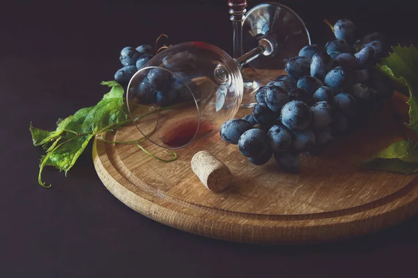 Dos copas de vino con vino tinto y hojas de vid decoradas con uvas sobre un escritorio de madera oscura — Foto de Stock