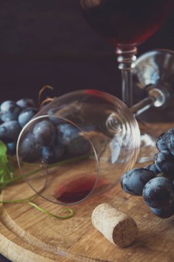 İki kadehlerin kırmızı şarap ve üzüm asma yaprağı koyu ahşap masa üzerine dekore edilmiştir.