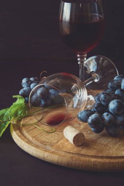 İki kadehlerin kırmızı şarap ve üzüm asma yaprağı koyu ahşap masa üzerine dekore edilmiştir.