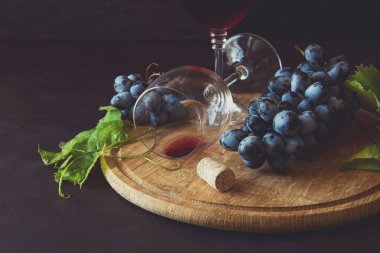 İki kadehlerin kırmızı şarap ve üzüm asma yaprağı koyu ahşap masa üzerine dekore edilmiştir.