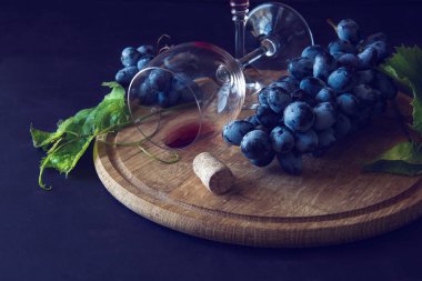 İki kadehlerin kırmızı şarap ve üzüm asma yaprağı koyu ahşap masa üzerine dekore edilmiştir.