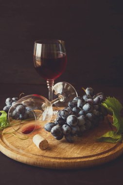 İki kadehlerin kırmızı şarap ve üzüm asma yaprağı koyu ahşap masa üzerine dekore edilmiştir.