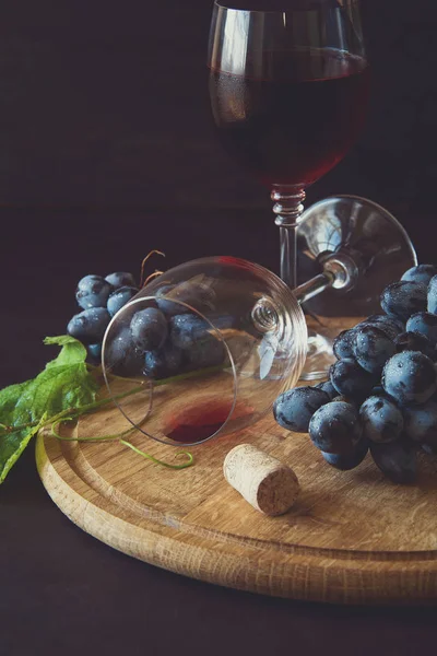 İki kadehlerin kırmızı şarap ve üzüm asma yaprağı koyu ahşap masa üzerine dekore edilmiştir.