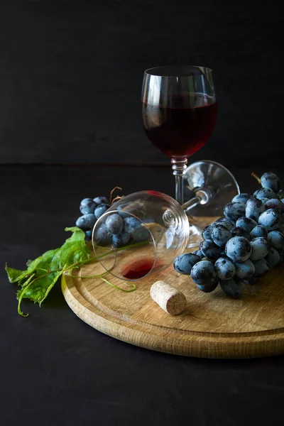 Dos copas de vino con vino tinto y hojas de vid decoradas con uvas sobre un escritorio de madera oscura — Foto de Stock