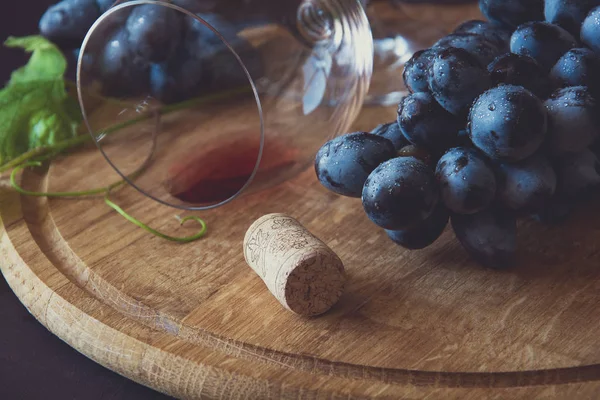 İki kadehlerin kırmızı şarap ve üzüm asma yaprağı koyu ahşap masa üzerine dekore edilmiştir.