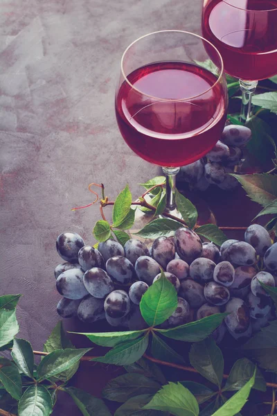 Natürmort kadehlerin, şişe, üzüm ve yaprakları kahverengi ahşap masa