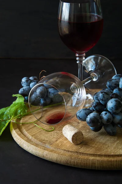 Dos copas de vino con vino tinto y hojas de vid decoradas con uvas sobre un escritorio de madera oscura — Foto de Stock