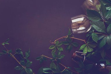 Natürmort kadehlerin, şişe, üzüm ve yaprakları kahverengi ahşap masa