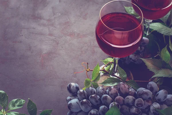 Bodegón con gafas de vino, botellas, uvas y hojas en escritorio de madera marrón — Foto de Stock