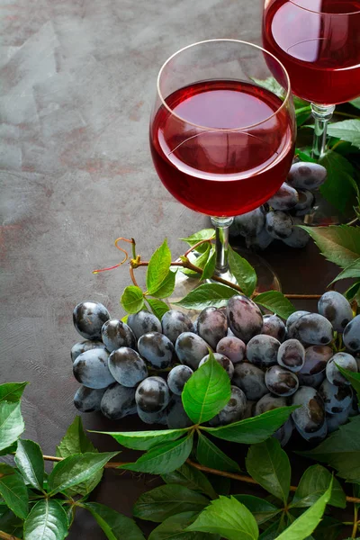 Martwa natura z kieliszki, butelki, winogron i pozostawia na brązowe biurko z drewna — Zdjęcie stockowe