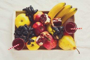 Elma, armut, muz, üzüm ve çarşaf üzerinde beyaz ahşap tepsi içinde nar meyve ile kırmızı taze meyve suyu. Üstten Görünüm. Sağlıklı yaşam konsepti