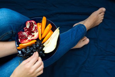 Sağlıklı beslenme kavramı. Kadınların elleri armut, üzüm, hurma ve nar meyve ile plaka tutarak. Üstten Görünüm