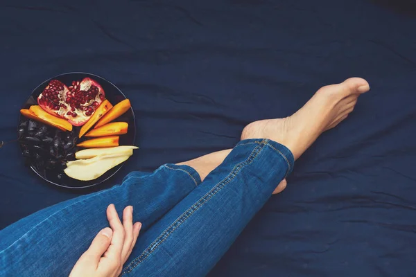 Hälsosamt ätande koncept. Kvinnors händer som håller plattan med päron, druvor, persimon och granatäpple frukt. Ovanifrån — Stockfoto