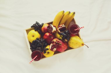 Elma, armut, muz, üzüm ve çarşaf üzerinde beyaz ahşap tepsi içinde nar meyve ile kırmızı taze meyve suyu. Üstten Görünüm. Sağlıklı yaşam konsepti