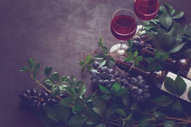 Natürmort kadehlerin, şişe, üzüm ve yaprakları kahverengi ahşap masa