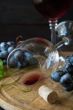 İki kadehlerin kırmızı şarap ve üzüm asma yaprağı koyu ahşap masa üzerine dekore edilmiştir.