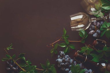 Natürmort kadehlerin, şişe, üzüm ve yaprakları kahverengi ahşap masa