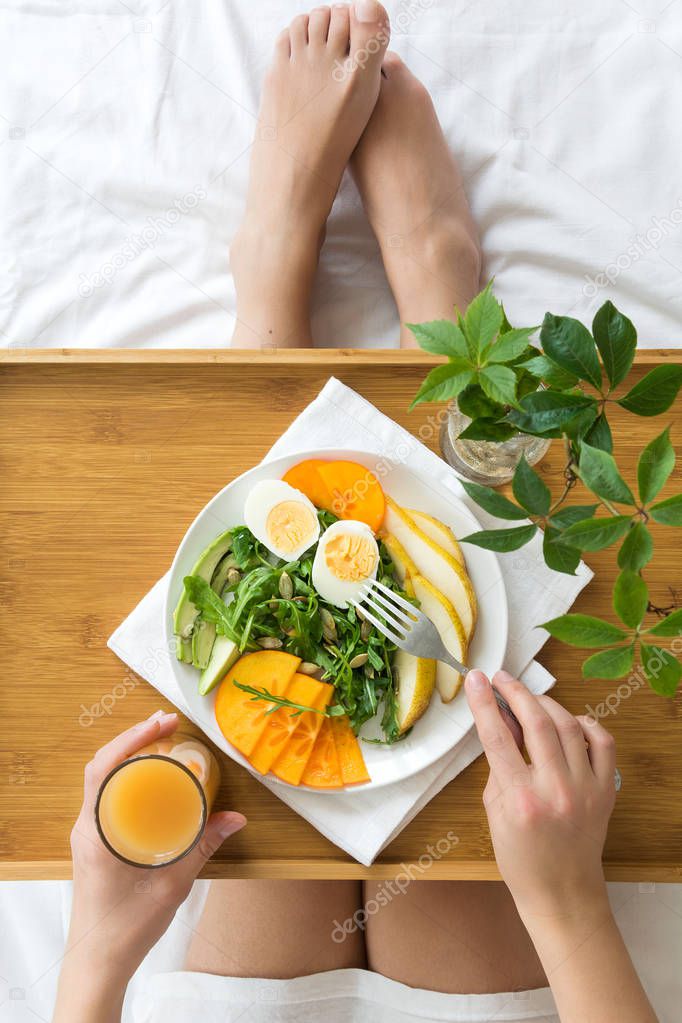 Healthy eating concept. Woman having breakfast in bed. Top view.