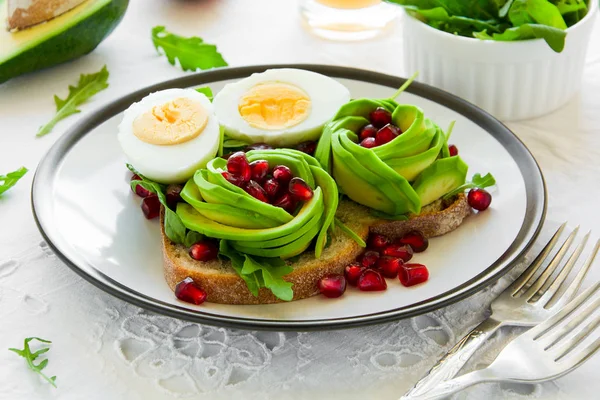 Avokado gül, haşlanmış yumurta ve beyaz masa örtüsü üzerinde taze salata ile tost