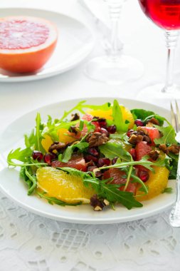 Roka, portakal, greyfurt, ceviz ve nar tohumları üzerinde beyaz masa örtüsü ile taze salata. Sağlıklı gıda.