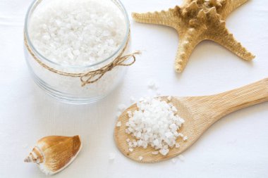 Sağlık ayarı. Deniz tuzu cam, sabun, havlu, zeytin yağı ve beyaz çiçekler arka plan dokulu. Kopya için alan. Düz yatıyordu