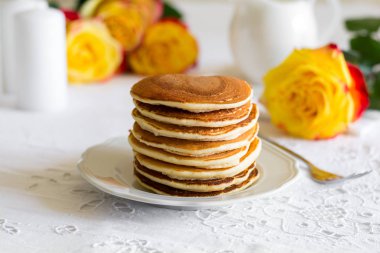 Ahududu, kırmızı kuş üzümü, krem ile krep yığını ve beyaz masa örtüsü üzerinde bal