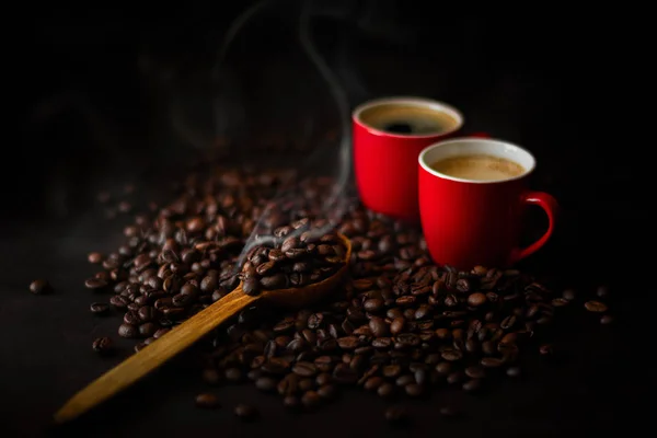 Duas xícaras vermelhas de café expresso com grãos de café em backgr de madeira escura — Fotografia de Stock